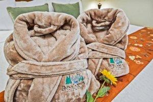 Box Canyon Lodge & Hot Springs branded velour robes are folded on top of a bed