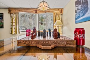 Close up of the carved wooden chess set and board sitting on top of the living room table next to two coke cans